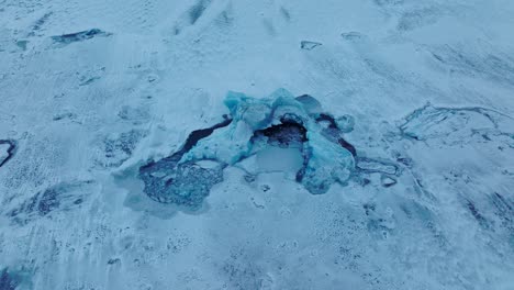 Aerial-top-view-over-icebergs-on-the-frozen-Jokulsarlón-lake-surface,-in-Iceland,-at-dusk
