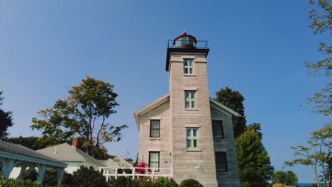 Bewegende-Aufnahme-Des-Leuchtturmmuseums,-Das-Sich-Am-Sodus-Point,-Einem-Urlaubsort-In-New-York,-An-Der-Landspitze-Am-Ufer-Des-Ontariosees-Zur-Linse-Neigt