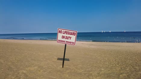 No-Lifeguard-sign-on-an-empty-beach-at-Sodus-point-New-York-vacation-spot-at-the-tip-of-land-on-the-banks-of-Lake-Ontario