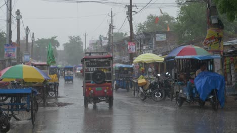 Starke-Regenfälle-Nach-Intensiver-Hitzewelle-In-Der-Ländlichen-Indischen-Stadt,-E-Rikschas-Parkten-Im-Regen-Am-Straßenrand