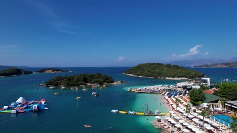 White-Sand-Beaches,-Azure-Sea,-Umbrella-Sunbathing,-Islands,-and-Boats-in-Ksamil-for-a-Perfect-Summer-Holiday,-Seaside-Bliss