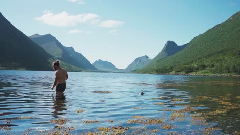Hombre-Caucásico-Nadando-Con-Un-Perro-Malamute-De-Alaska-En-El-Lago-Gryllefjord-En-Senja,-Noruega