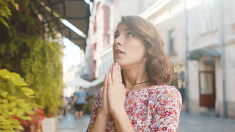 Portrait-of-woman-praying-with-closed-eyes-to-God-asking-for-blessing,-help,-forgiveness-outdoors