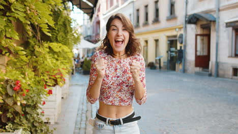 Young-woman-shouting,-celebrating-success-winning-goal-achievement-good-victory-news-in-city-street