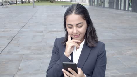 Young-businesswoman-using-smartphone-and-smiling