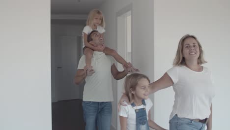 Happy-family-couple-with-two-kids-coming-into-new-apartment