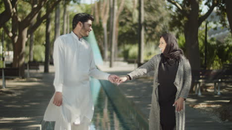 Seitenansicht-Eines-Jungen-Muslimischen-Paares,-Das-Sich-Im-Park-An-Den-Händen-Hält.