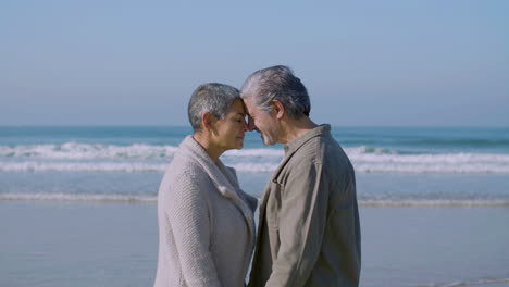Cheerful-senior-man-and-woman-embracing-each-other-on-beach
