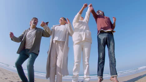 Happy-senior-couples-standing-in-line-on-beach-and-jumping-up