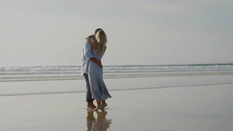 Happy-Caucasian-couple-hugging-and-dancing-at-seashore.