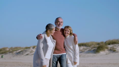 Smiling-senior-man-and-women-hugging-on-sandy-shore