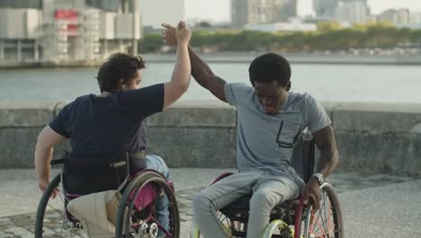 Happy-couple-holding-hands-and-spinning-on-wheelchairs