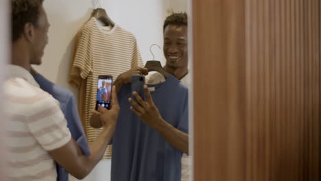 Happy-black-guy-taking-selfie-in-dressing-room-in-store.