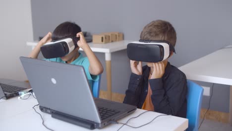 Two-classmates-putting-on-VR-glasses-at-desk