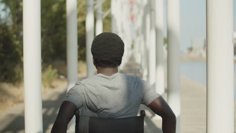 Rear-view-of-African-American-man-using-wheelchair-walking