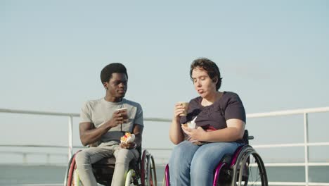 Happy-couple-with-disability-drinking-coffee-and-eating-pastry