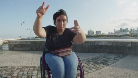 Portrait-of-young-woman-dancing-using-wheelchair-outdoors