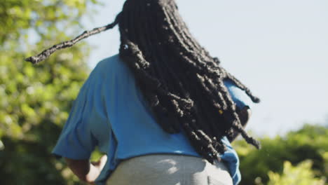 Back-view-of-woman-with-dreadlocks-running-up-stairs-in-nature