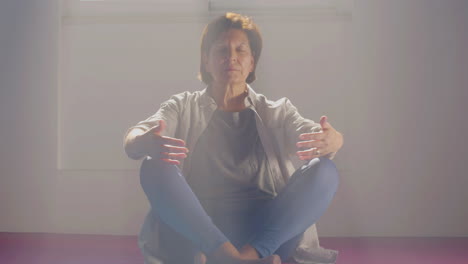 Senior-woman-meditating-in-lotus-position-in-gym