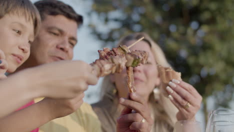 Happy-family-toasting-shaslik,-meat-and-hotdog-at-barbecue-party
