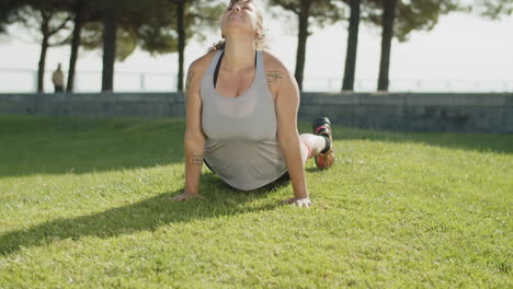Front-view-of-Caucasian-woman-stretching-back-on-lawn-in-park