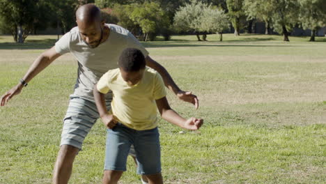 Father-and-son-playing-ball-game,-running-towards-camera.