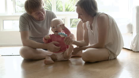 Funny-little-baby-girl-sitting-on-floor-with-parents