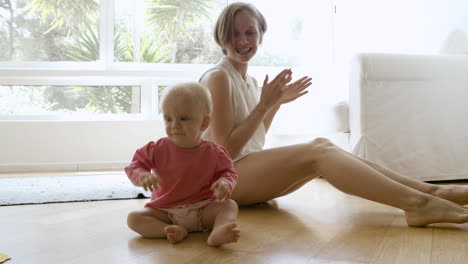 Glückliche-Mutter-Fasst-Die-Hände,-Spielt-Mit-Dem-Baby-Und-Sitzt-Auf-Dem-Boden