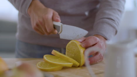 Closeup-of-male-hands-cutting-juicy-lemon-on-wooden-board.