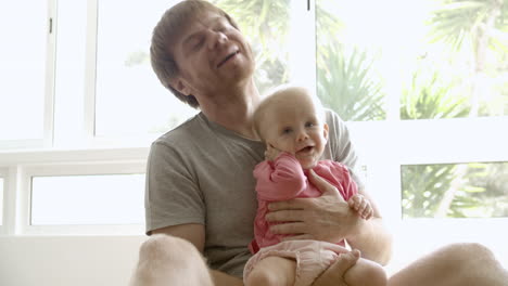 Happy-father-holding-baby-on-hands,-playing,-talking-with-girl