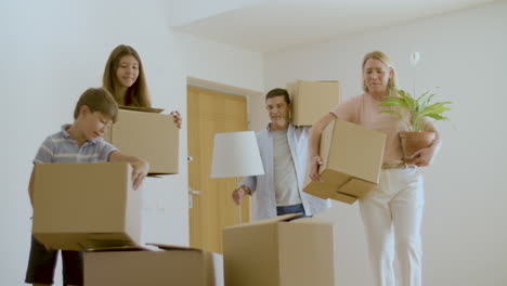 Cheerful-family-entering-new-apartment-with-cardboard-boxes