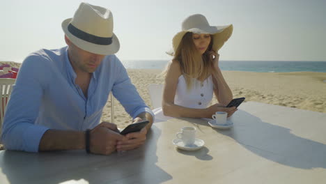 Couple-sitting-at-table-and-using-smartphones