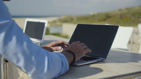 Cropped-shot-of-couple-using-laptops-on-beach