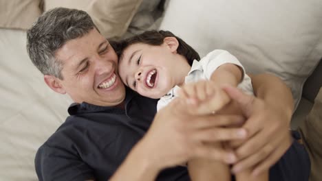 Joyful-dad-cuddling-and-tickling-laughing-little-son