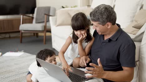 Cheerful-kids-interrupting-dads-work-with-laptop
