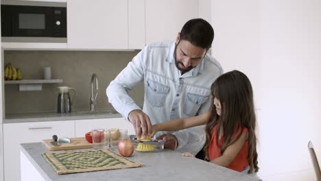 Young-dad-and-daughter-enjoying-cooking
