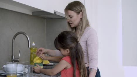 Cheerful-mom-teaching-girl-to-wash-dish