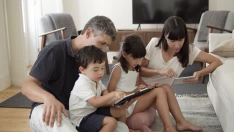 Family-couple-and-two-kids-using-digital-tablets