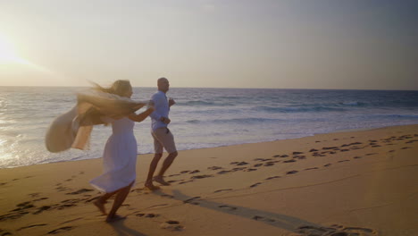 Happy-barefoot-couple-running-on-sand-at-seaside