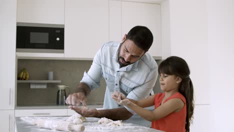 Happy-focused-dad-teaching-daughter-to-bake