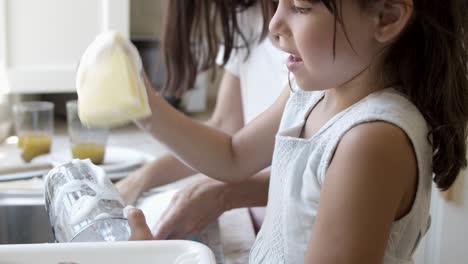 Konzentriertes-Mädchen-Hilft-Ihrer-Mutter-Beim-Geschirrspülen