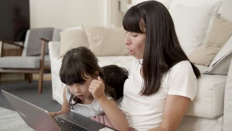 Mom-teaching-daughter-typing-text-on-laptop