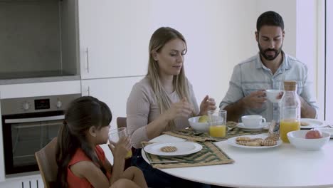Young-parents-and-little-kid-enjoying-breakfast-together
