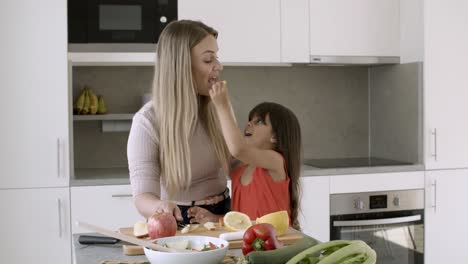 Mutter-Hilft-Ihrer-Kleinen-Tochter-Beim-Schneiden-Von-Gemüse-Für-Den-Salat