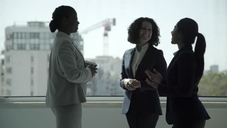 Cheerful-multiethnic-businesswomen-talking-in-office