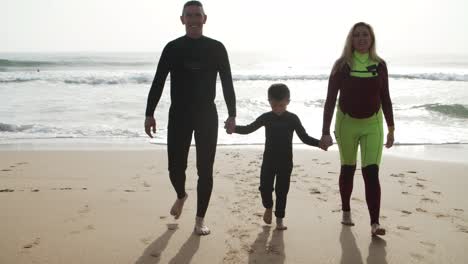 Happy-family-holding-hands-and-walking-on-beach