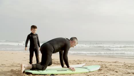 Father-and-little-son-lying-on-surfboard