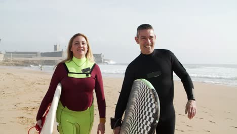 Happy-man-and-woman-with-surfboards-on-beach