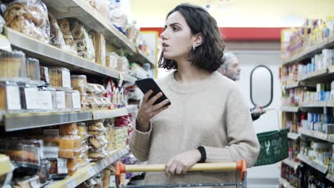 Mujer-Usando-Un-Teléfono-Inteligente-En-Una-Tienda-De-Comestibles