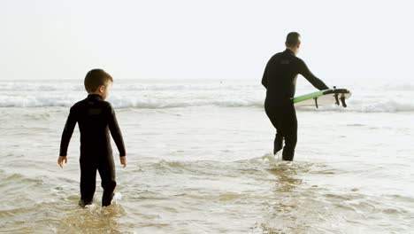 Father-and-son-with-surfboard-in-water